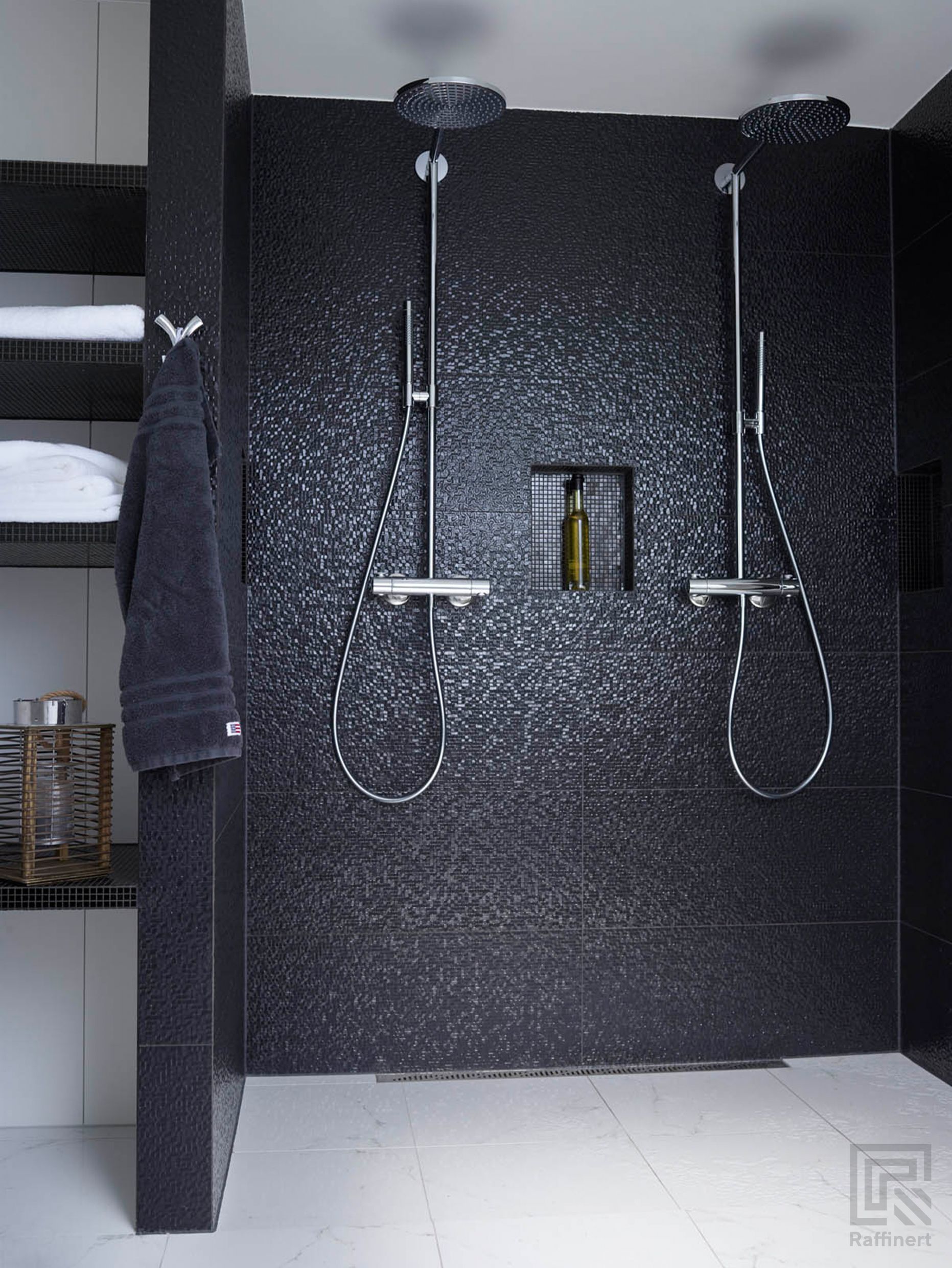 Dobbel dusj med mosaikfliser i sort. Midt i dusjen en nisje til sjampooflasker og såpe. Ved siden er det nisjer til håndklær laget med de samme flisene.