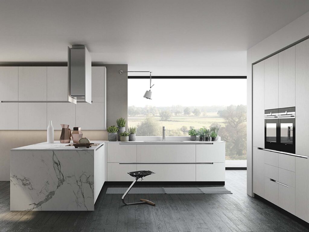 Lekkert hvitt kjøkken, med marmorbenkeplate ned til gulvet. Vinduer fra gulv til tak, men lekker utsikt omkranser kjøkkenet.