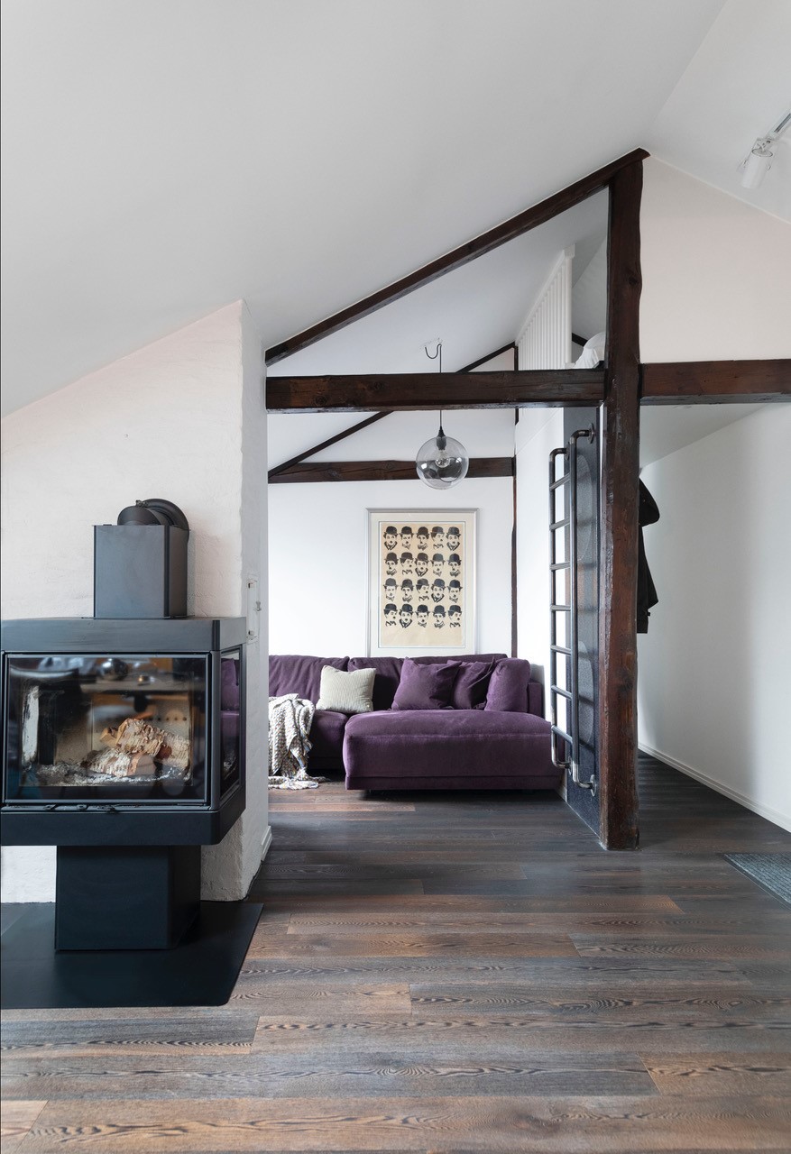 Lekker auberginefarget sofa i skjønn harmoni med mørk tregulv. Detaljer med tapet og midd stige til hemsen