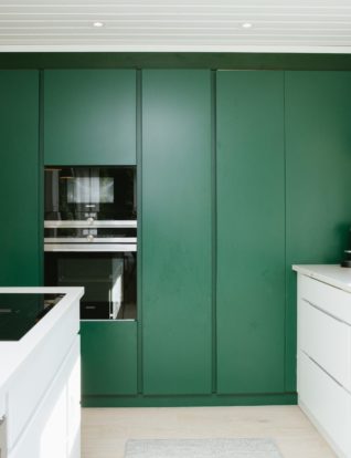 Flaskegrønne høyskap er plassert langsmed en vegg på kjøkken